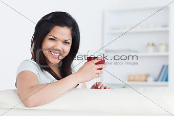Woman holding a glass of red wine with one hand while resting he