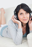 Woman laying on a couch while wearing headphones on