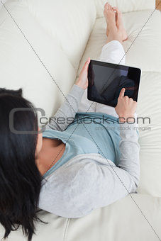 Woman lying on a sofa while touching a tactile tablet