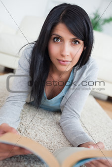 Woman holding a book while laying on the floor