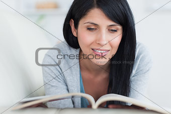 Woman reading a book while resting on a sofa