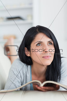 Woman holding a magazine and lying on a sofa