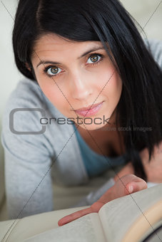 Woman reading a book while resting on a white sofa