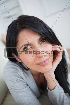 Woman holding her head with her fist and lying on a couch