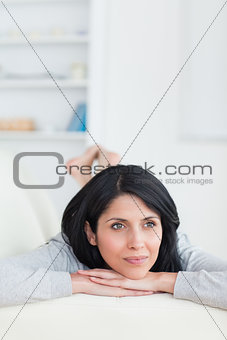 Woman laying on a sofa while holding her head
