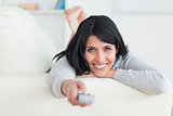 Woman pressing on a television remote while laying on a couch