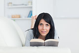 Woman holding a book while resting on a couch