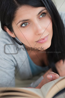 Woman holding up a book while lying on a sofa