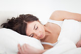 Brunette woman lying on a bed while sleeping
