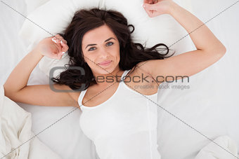 Peaceful brunette woman stretching her body while lying