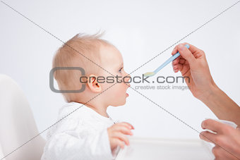Cute baby sitting on a highchair while being fed