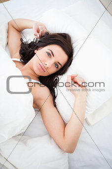 Brown-haired woman lying while stretching her arms
