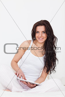 Happy brunette woman touching her tablet pc while sitting