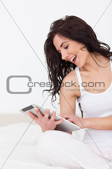 Cheerful woman holding her tablet pc while sitting