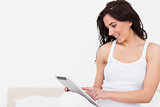 Smiling brunette woman sitting while using her touchscreen