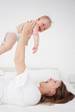 Happy woman holding her baby while lying