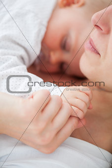 Peaceful woman lying with her baby who is sucking a pacifier