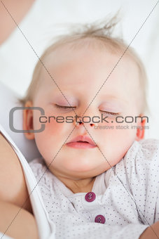 Beautiful baby sleeping in the arms of her mother