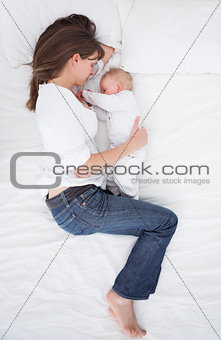 Brunette woman lying next to her baby