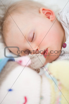 Cute baby sleeping next to her stuffed teddy bear