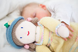 Baby sleeping while holding a plush doll