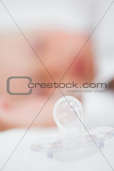 Clear pacifier being placed next to a baby
