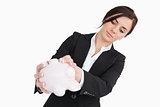 Young woman in suit emptying a piggy bank