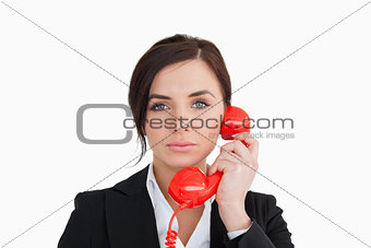 Attractive woman in suit using a red dial telephone