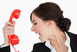 Woman in suit shouting against a red dial telephone