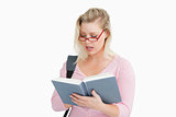 Serious woman reading a book while wearing glasses