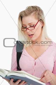 Serious woman wearing glasses while reading a book