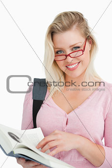 Happy young woman wearing glasses while holding a novel