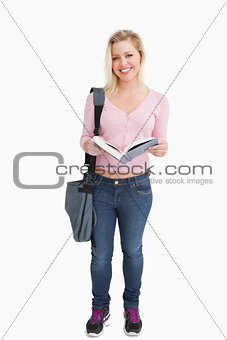 Happy woman standing while holding a novel