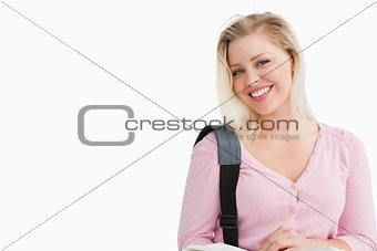 Happy woman looking at the camera while holding a book