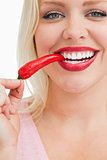 Cheerful blonde woman eating a chili