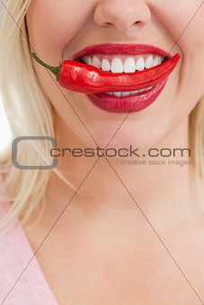 Happy woman placing a red chili in her mouth