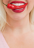 Happy blonde woman placing a chili between her teeth