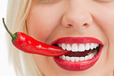 Smiling woman holding a chili with her teeth