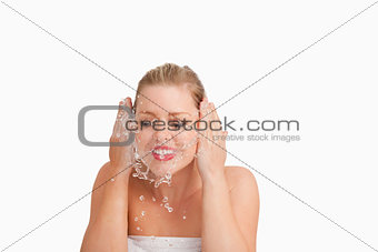 Smiling blonde woman splashing her face