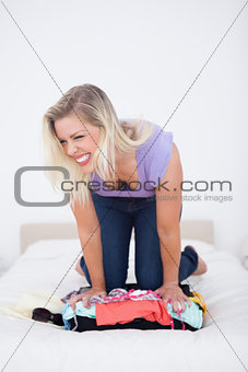 Blonde trying hard to close her suitcase