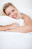 Young blonde smiling while embracing a pillow