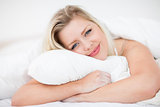 Blonde smiling while embracing a pillow