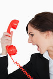 Woman in suit screaming on a red dial telephone