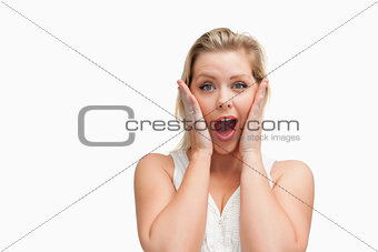 Surprised blonde woman putting her hands on her cheeks
