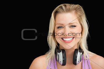 Happy blonde woman standing upright with headphones
