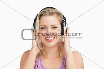 Smiling blonde woman placing her hands on her headphones
