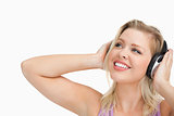 Smiling blonde woman looking up while listening to music