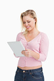 Smiling blonde woman standing while touching her tablet pc