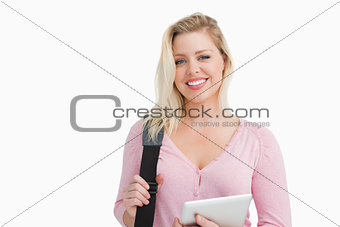 Blonde woman holding a tablet computer and a shoulder bag