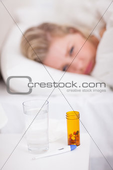 Medicines and thermometer on a beside table
